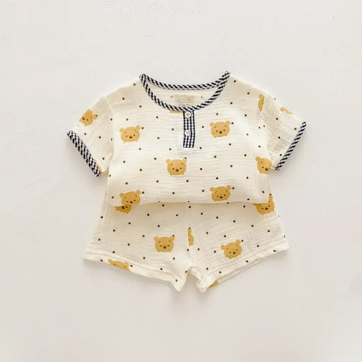 Baby outfit with shirt and shorts featuring teddy bear pattern on a light gray background