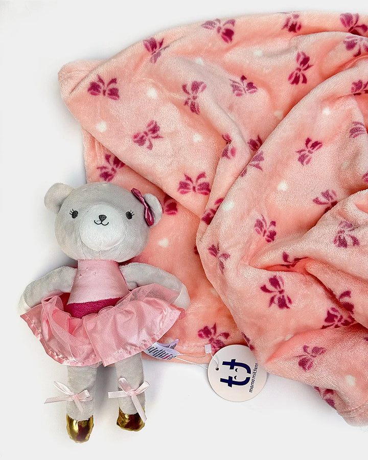 A plush pink blanket with a floral pattern and a stuffed toy bear next to it.